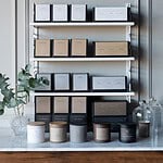 Hylla med doftljus från Wikholm Form, inklusive doftljuset SANDALWOOD, i en elegant miljö med växter och stilren inredning.