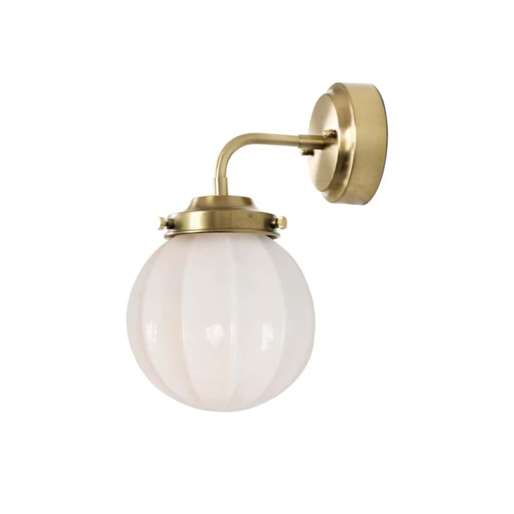 Vägglampa MARIT från Strömshaga i mässingsfinish med runt opalglas. En elegant lampa som sprider ett mjukt ljus och skapar en inbjudande atmosfär.