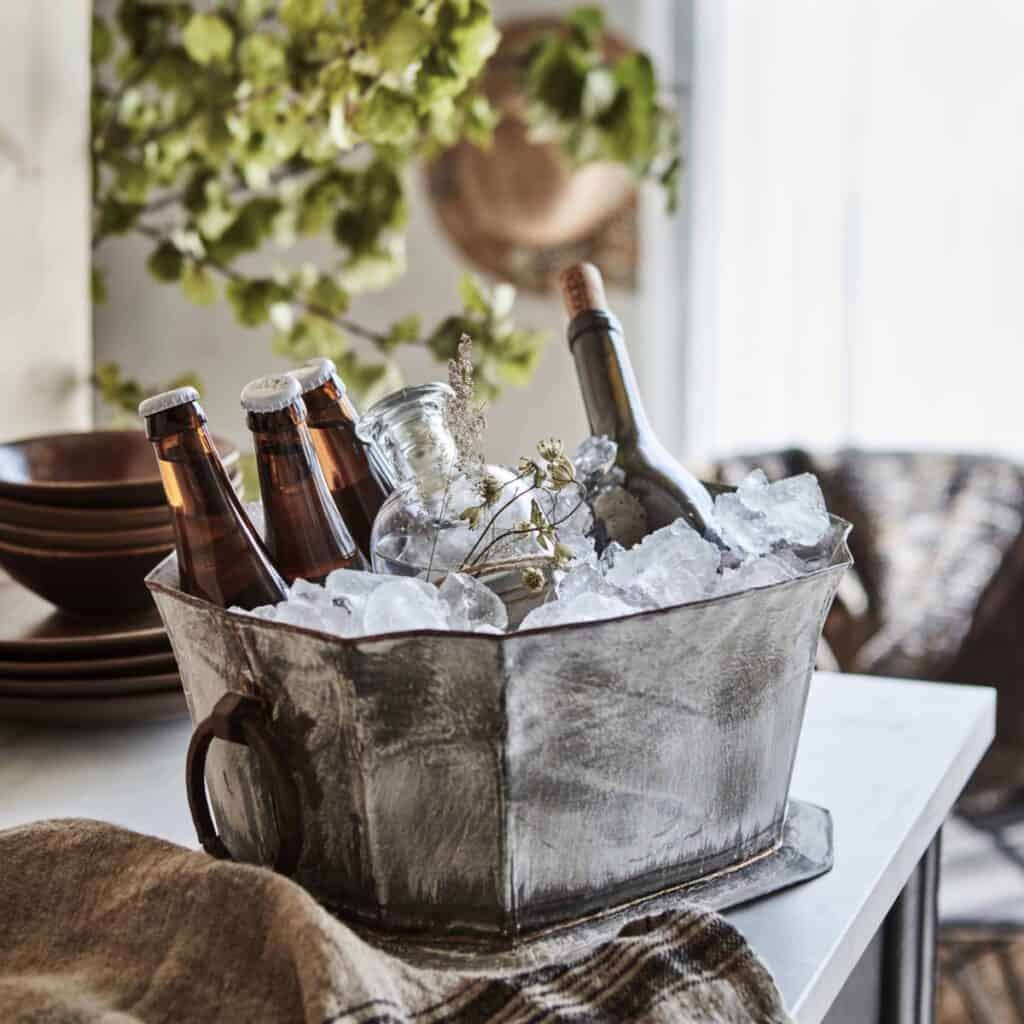 Kylda drycker serverade i en rustik ishink, perfekt för att hålla dryckerna svala under sensommarens fester och kräftskivor.