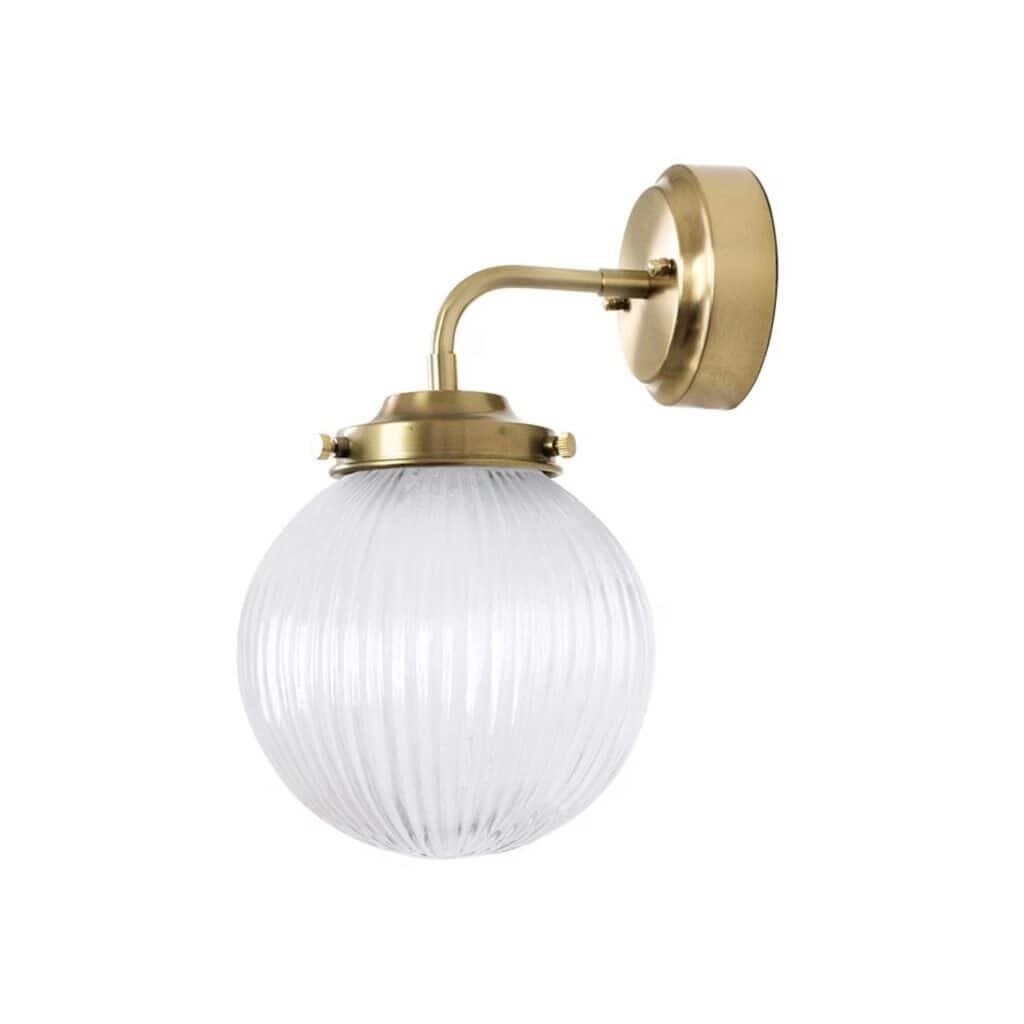 Vägglampa med rund glasglob och mässingsfärgad armatur, en elegant belysning som passar badrum och andra rum.
