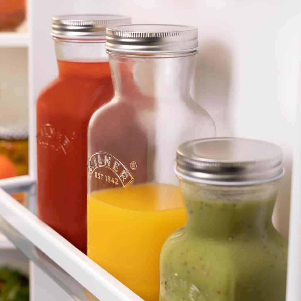 Kilner glasflaskor i kylskåp fyllda med olika drycker som juice, tomatsås och smoothie.