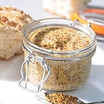 Kilner glasburk fylld med grovkornig senap, serverad med bröd och en sked för enkel användning.
