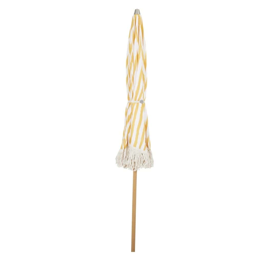 Ihopfällt gulrandigt parasoll från Brafab med fransar, ståendes upprätt med den naturliga trästången synlig.