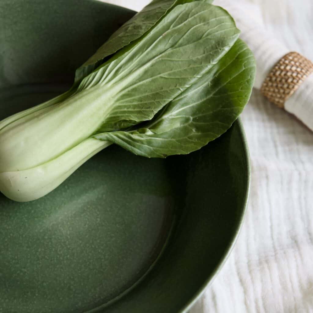 Serveringsskål Annabelle i grönt stengods från Affari of Sweden, elegant dukad med pak choi och linneservett med flätad servettring.