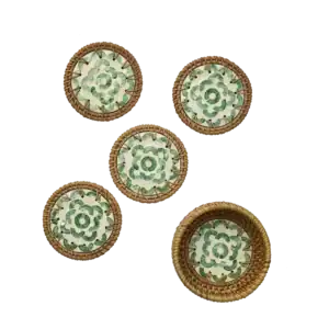 Fem glasunderlägg med grön snäckdesign och flätad kant i rotting