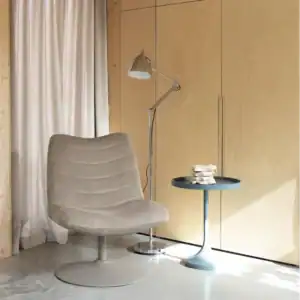 Golvlampa READER i krom från Zuiver placerad bredvid en beige fåtölj i ett modernt vardagsrum.