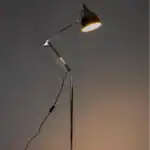 Golvlampa READER i krom från Zuiver, tänd i ett mörkt rum som skapar en varm och inbjudande atmosfär.