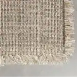 Baksidan av matta HAIRY i beige från Zuiver med flätad väv och dekorativa fransar.