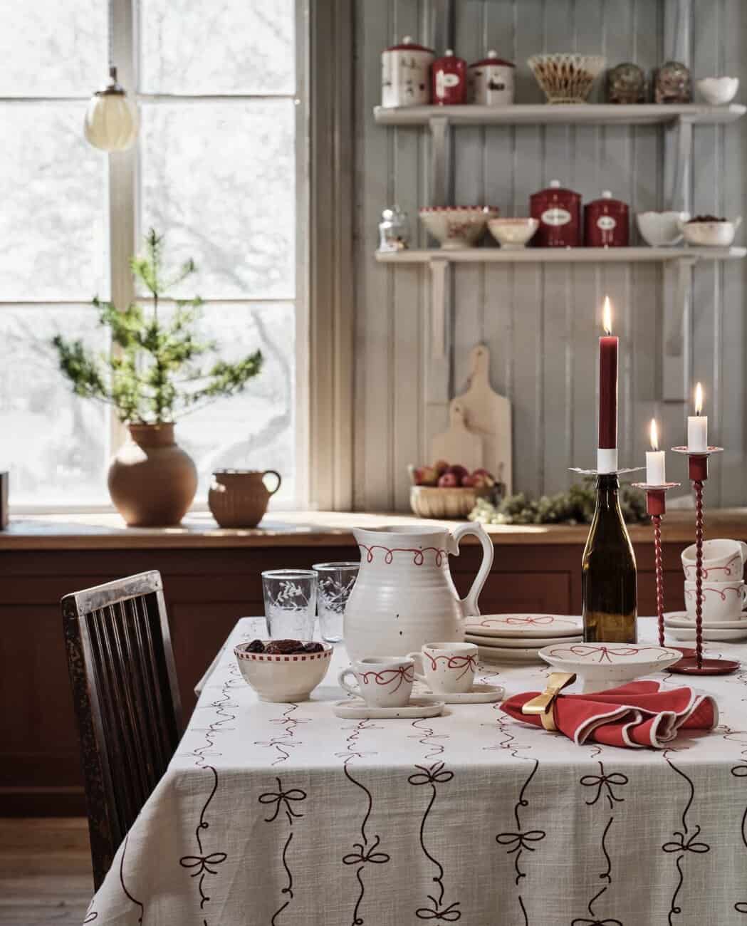 Adventsstämning hemma med dukat bord, röda ljus och vinterkänsla i köket.