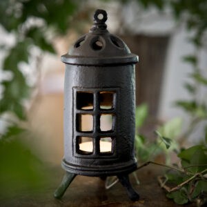 Värmeljuslykta i gjutjärn formad som en liten kamin med fönster, från Strömshaga.