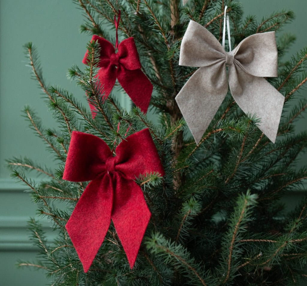 Röda rosetter i granen – juldekoration i textil från Hemlängtan.
