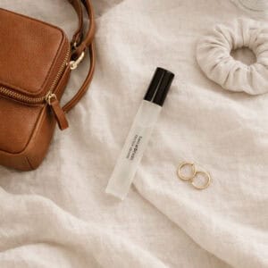 Eau de Parfum DESIRE från Washologi tillsammans med brun läderväska och guldringar på ljust tyg