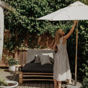Parasoll i trä med off-white duk på grönskande uteplats