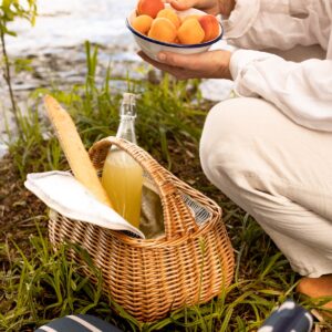 Picknickkorg Molly i flätad pil med baguette och dryck under picknick vid sjö