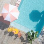 Randigt parasoll i rosa och vitt vid pool på träaltan med utemöbler