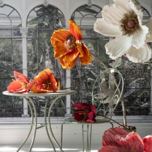Vallmo konstblomma vit som golvdekoration tillsammans med stora vallmoblommor i rött och orange.