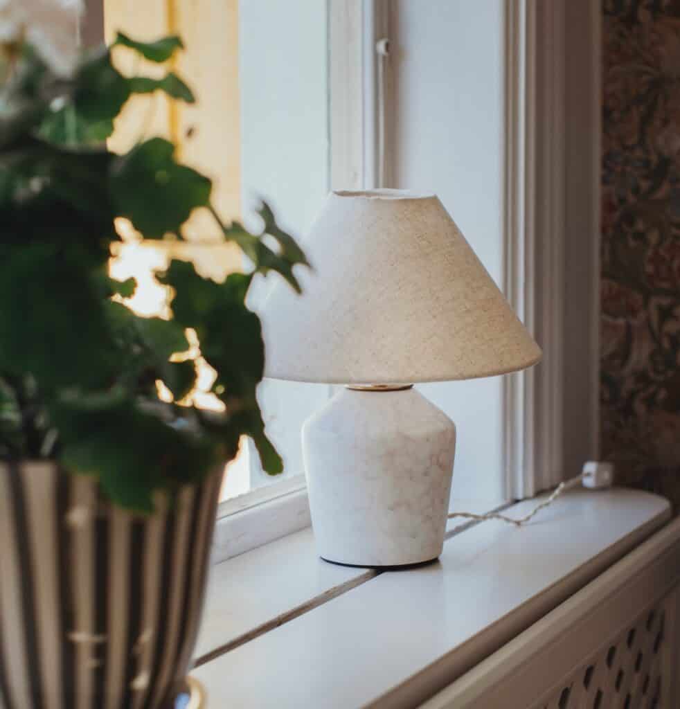 Liten bordslampa på fönsterbräda med mjukt ljus och lantlig känsla